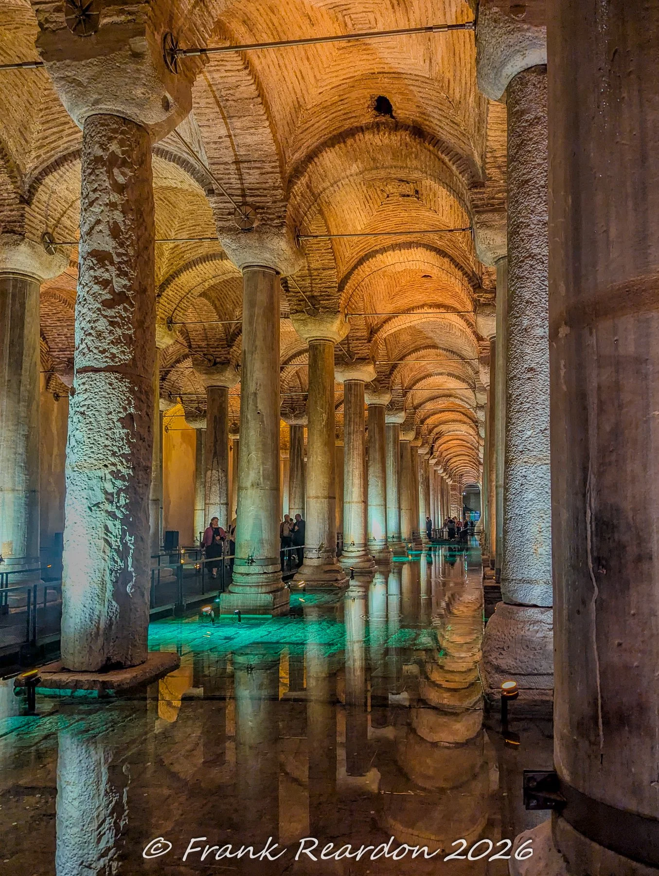 A wide-angle view looking down one of the grand, colonnaded aisles of the Basilica Cistern with visitors exploring the historic site.