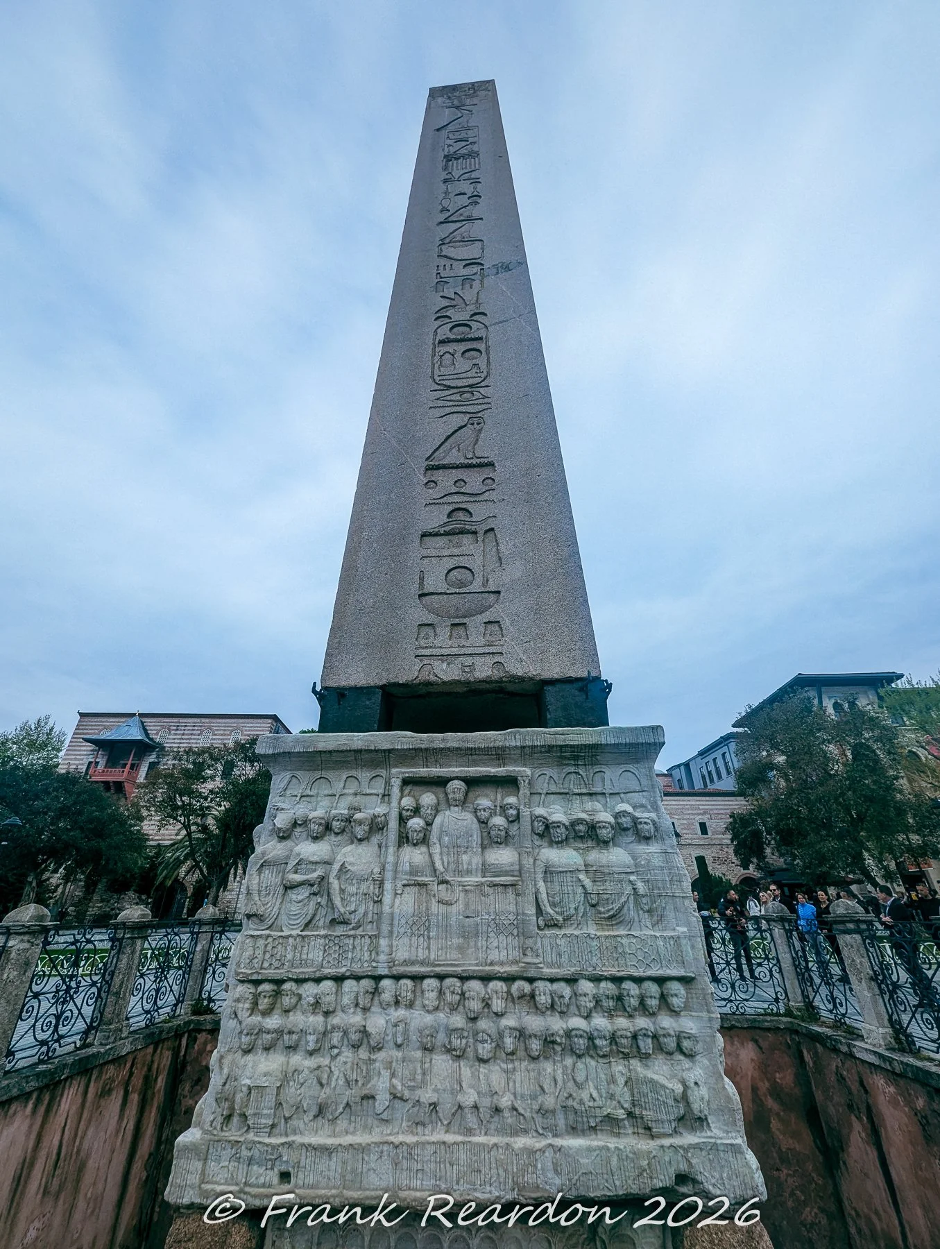 A dramatic upward angle of the Walled Obelisk (Column of Constantine Porphyrogenitus) with its stone relief base, located in the historic Hippodrome of Constantinople (Sultanahmet Square).
