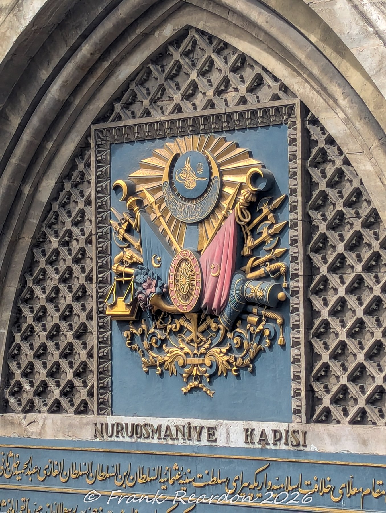A detailed shot of the intricate, gold-accented Ottoman imperial crest mounted above the gateway of the Grand Bazaar (Kapalıçarşı).