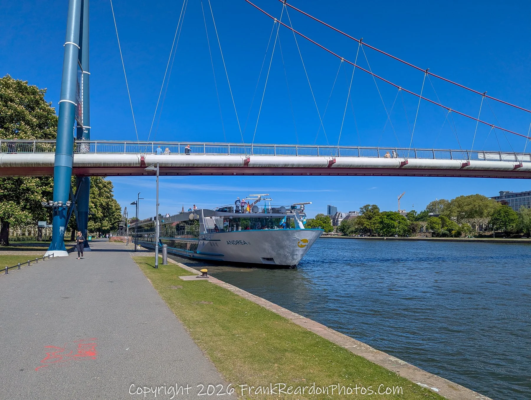 Riverboat Under Pedestrian Bridge (Wide View)
“Beneath the Bridge – Life Along the Main”