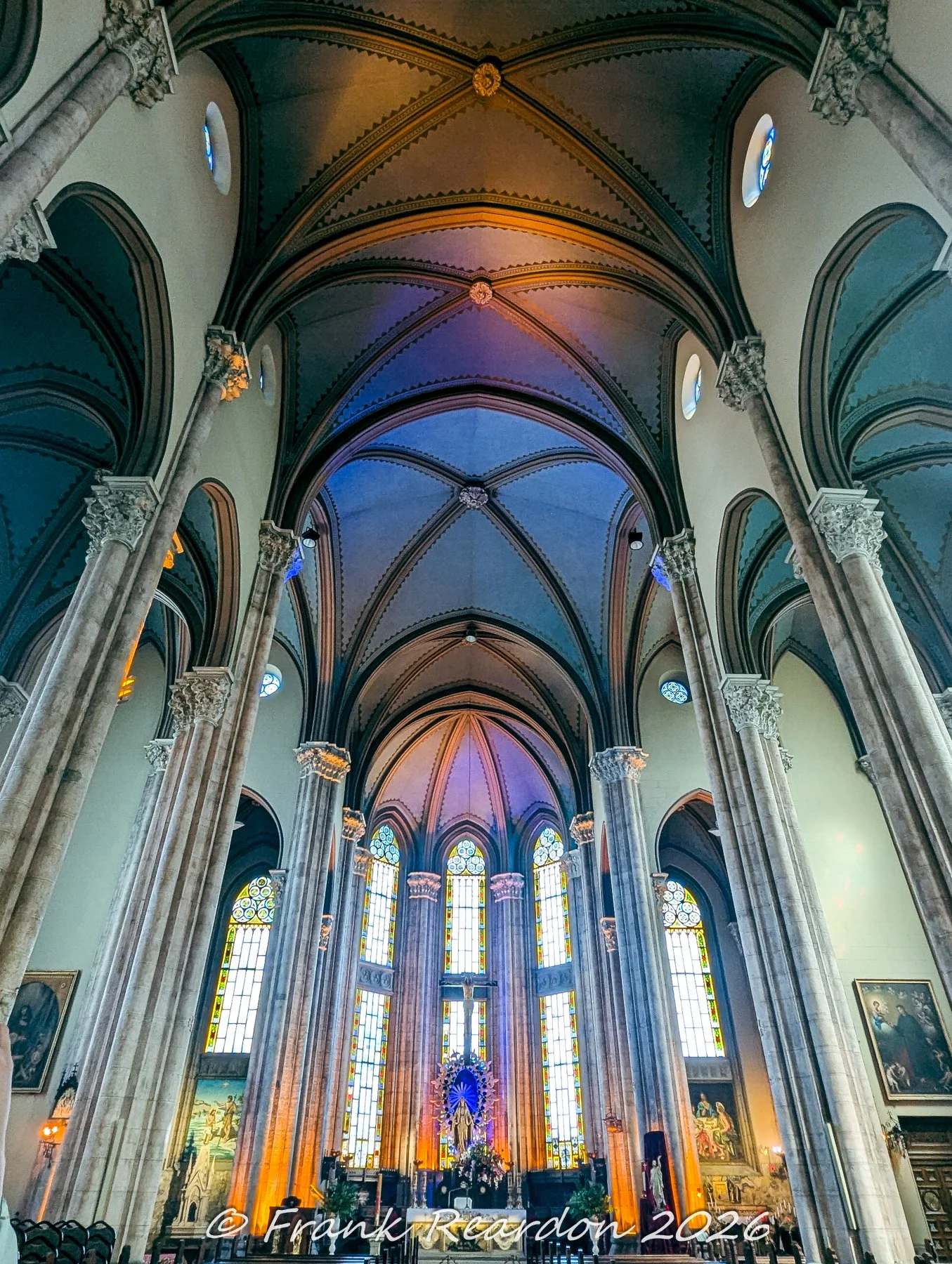 Looking up at the soaring Gothic ribbed vaults, soaring stone columns, and stained-glass windows inside the main nave of the Church of Saint Anthony of Padua.