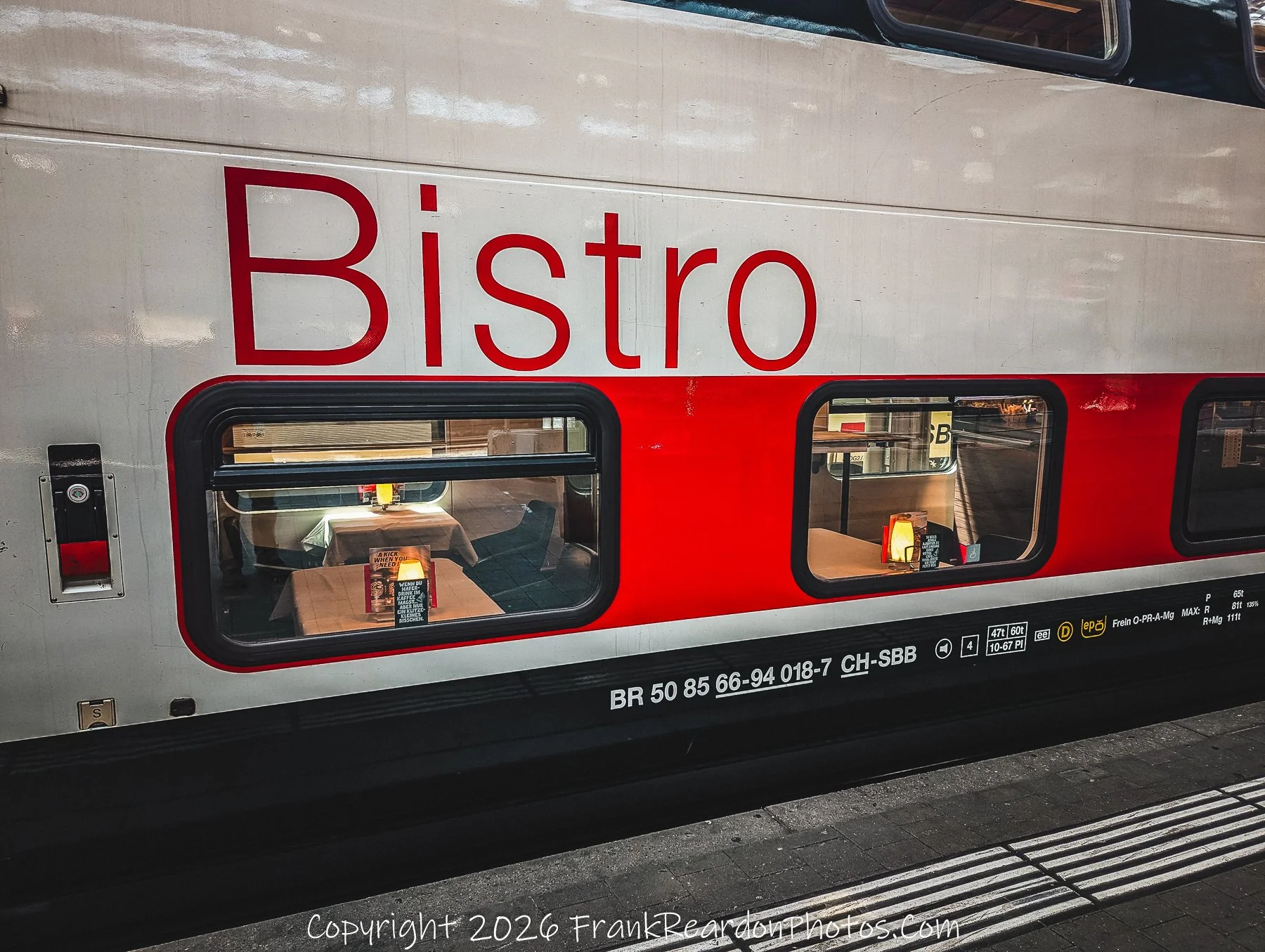 "Dining on Rails" A close-up of the exterior of an SBB train, clearly showing the "Bistro" branding and a peek into the warm, illuminated interior dining car tables.