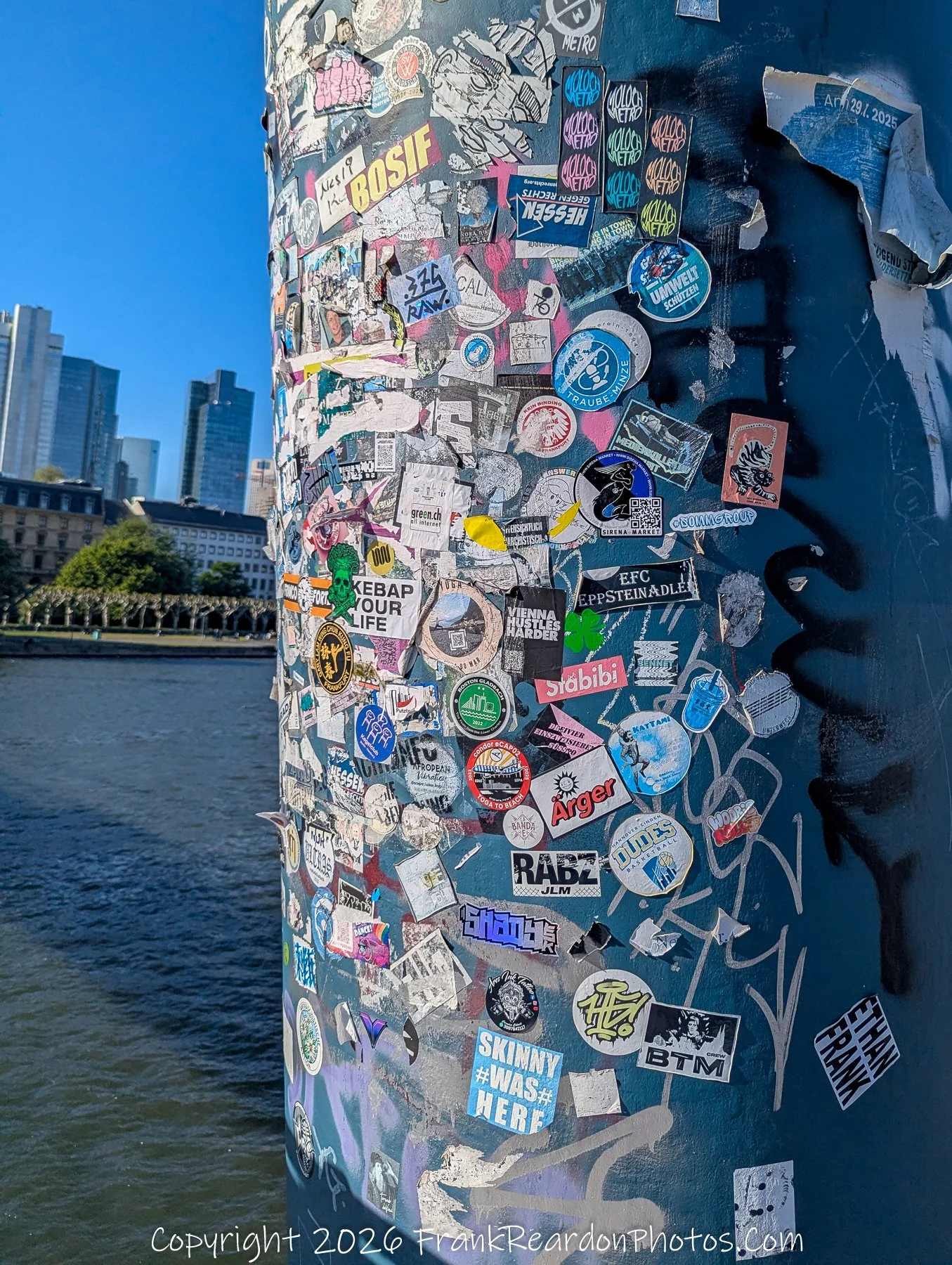 Sticker-Covered Pillar by the Main River.
Urban Collage on the Waterfront