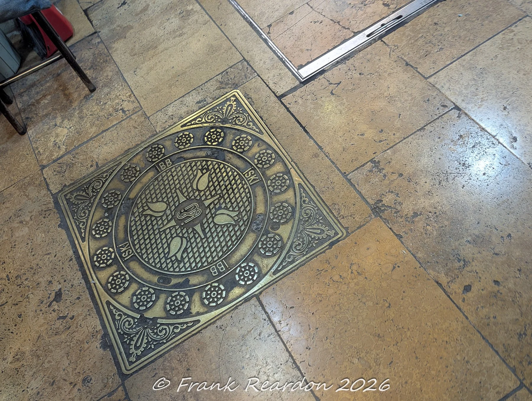 An intricate, brass-accented municipal utility cover featuring traditional tulip motifs and Istanbul Metropolitan Municipality (İBB) markings set into the stone floor of the Grand Bazaar.