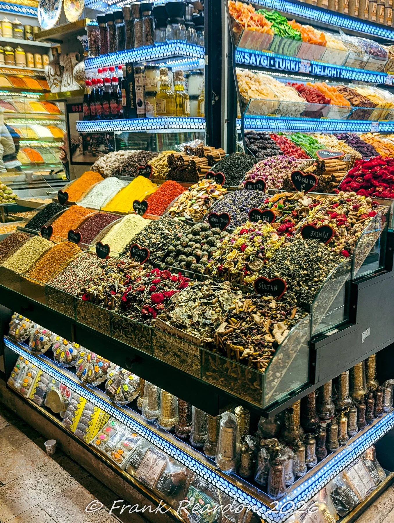 Slanted glass bins holding an array of colorful herbal tea blends, winter teas, and aromatic floral infusions inside the Spice Bazaar.