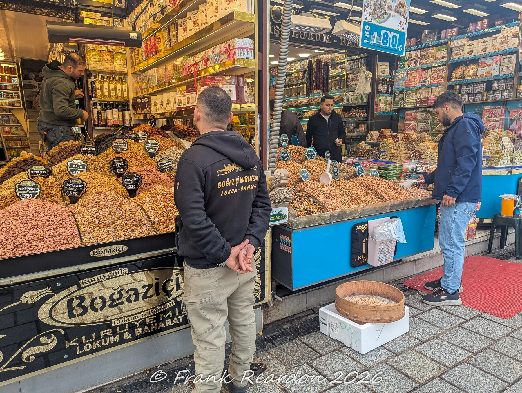 Shoppers browsing the vibrant selection of dried nuts, spices, and Turkish delights at the Boğaziçi Kuruyemiş Lokum & Baharat storefront.