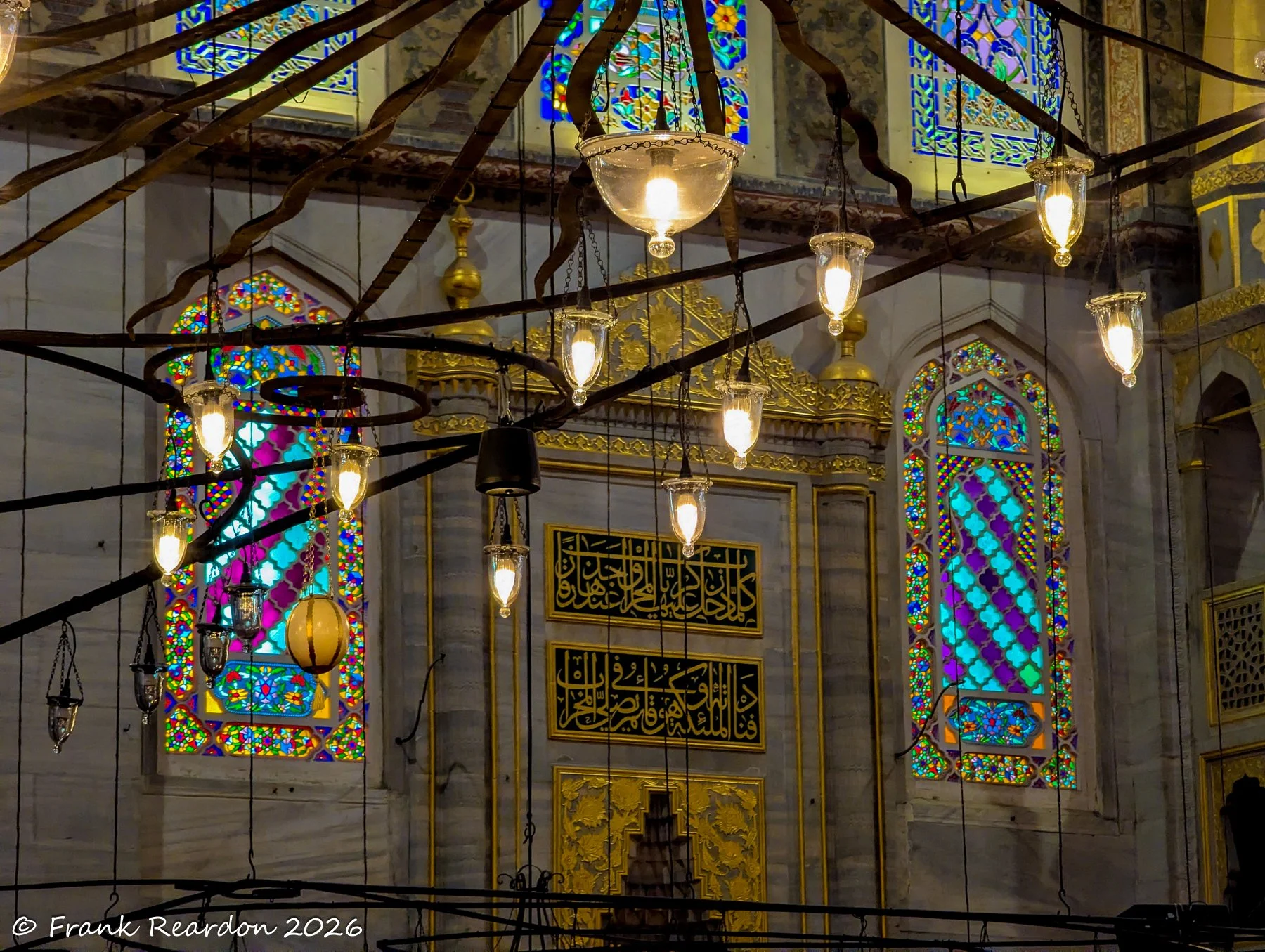 An artistic composition featuring traditional hanging light fixtures against a backdrop of decorative wall panels and blue-toned windows.