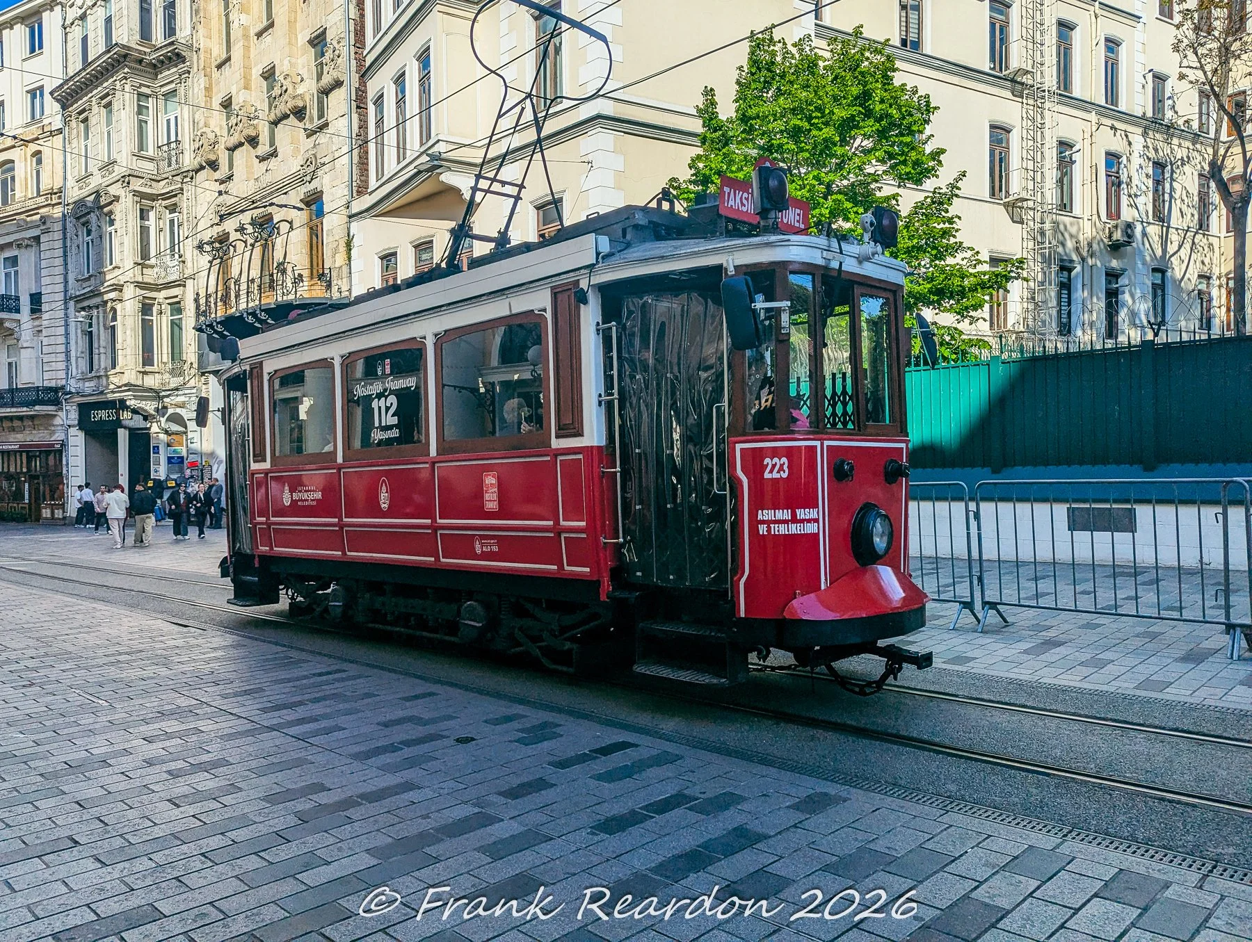The front end of the historic red tram car marked with number 223, captured as it navigates the streetscape.