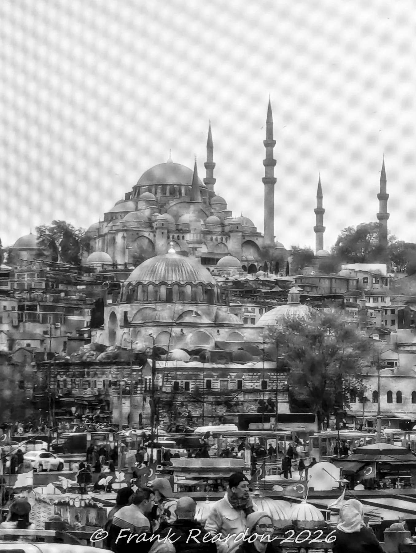 A black-and-white distant view of the grand Süleymaniye Mosque overlooking the bustling streets and market stalls of Istanbul.