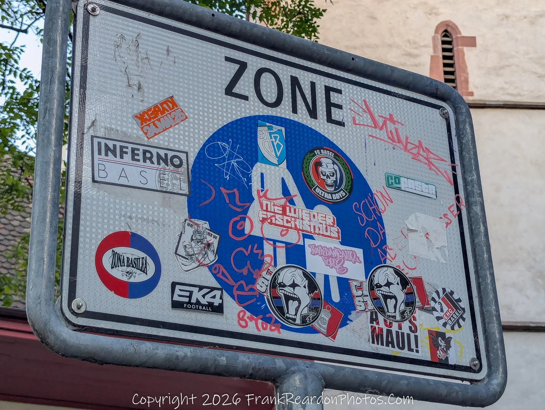 "Graffiti/Sticker-Covered Zone Sign" A "ZONE" traffic sign covered in various stickers and graffiti.