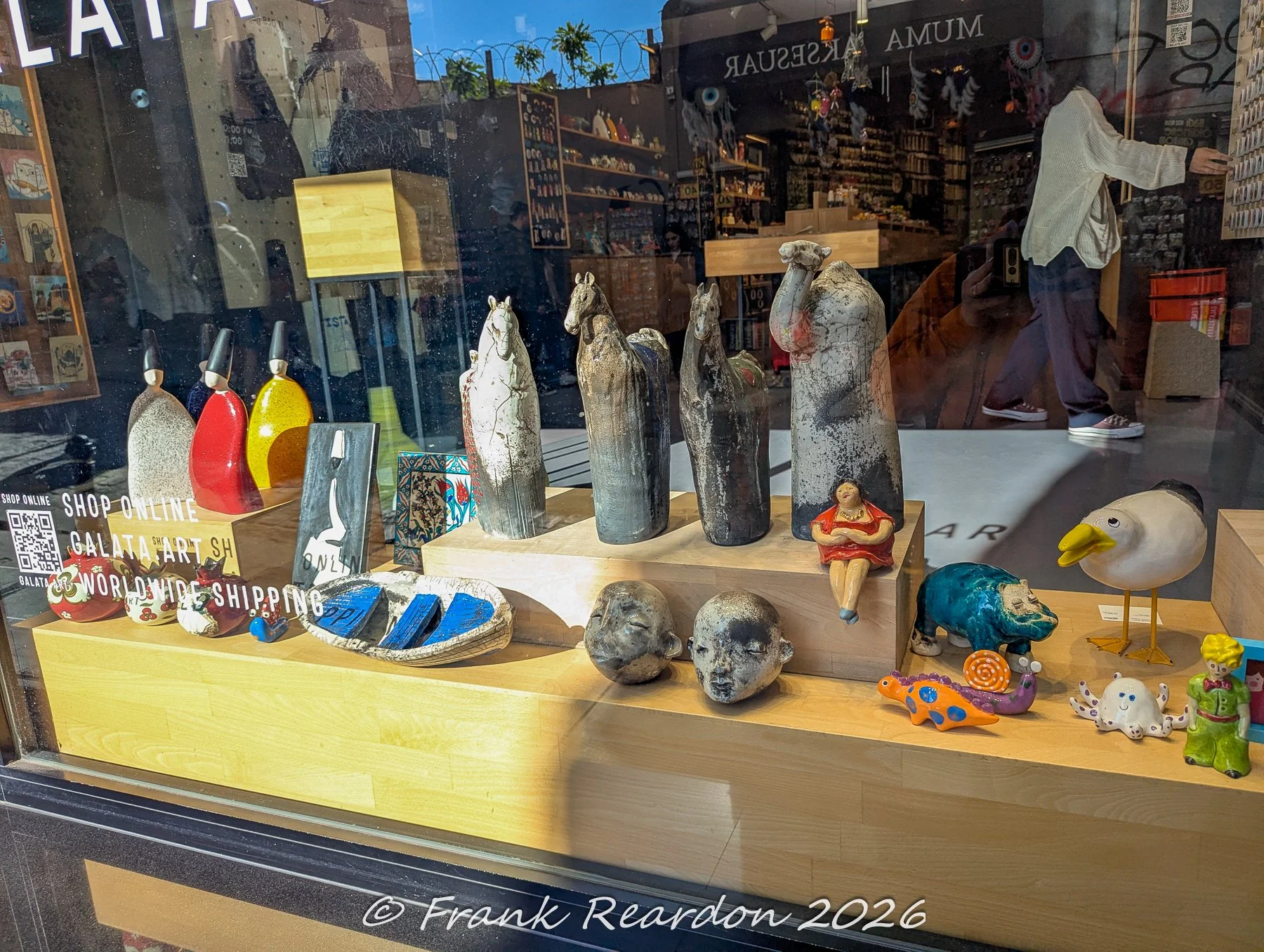 A shop window display showcasing various handcrafted ceramic sculptures, animal figures, and artistic pottery pieces in Istanbul.