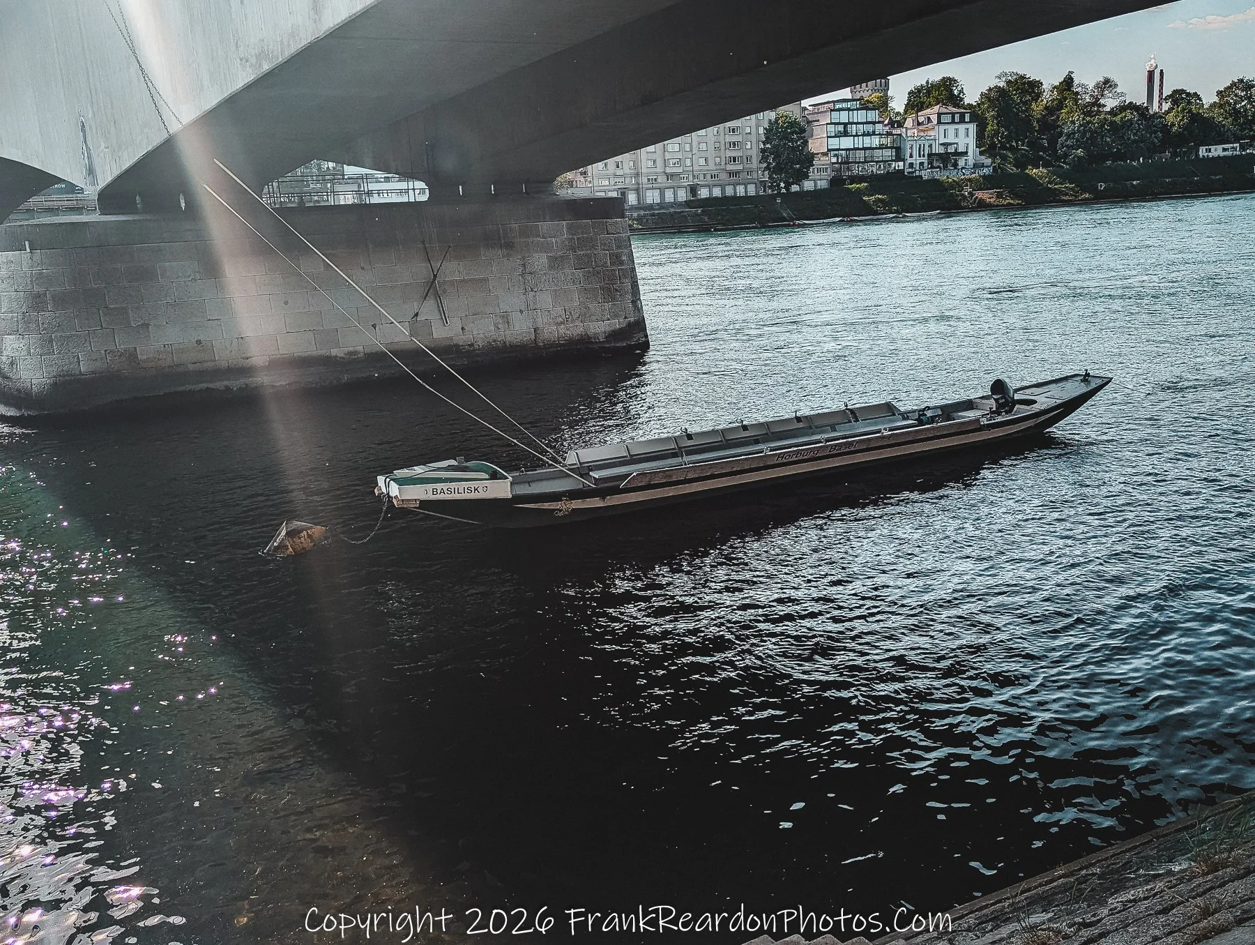 “Basilisk Beneath” A lone ferry waits under the bridge, tethered to the river’s quiet strength and history.
