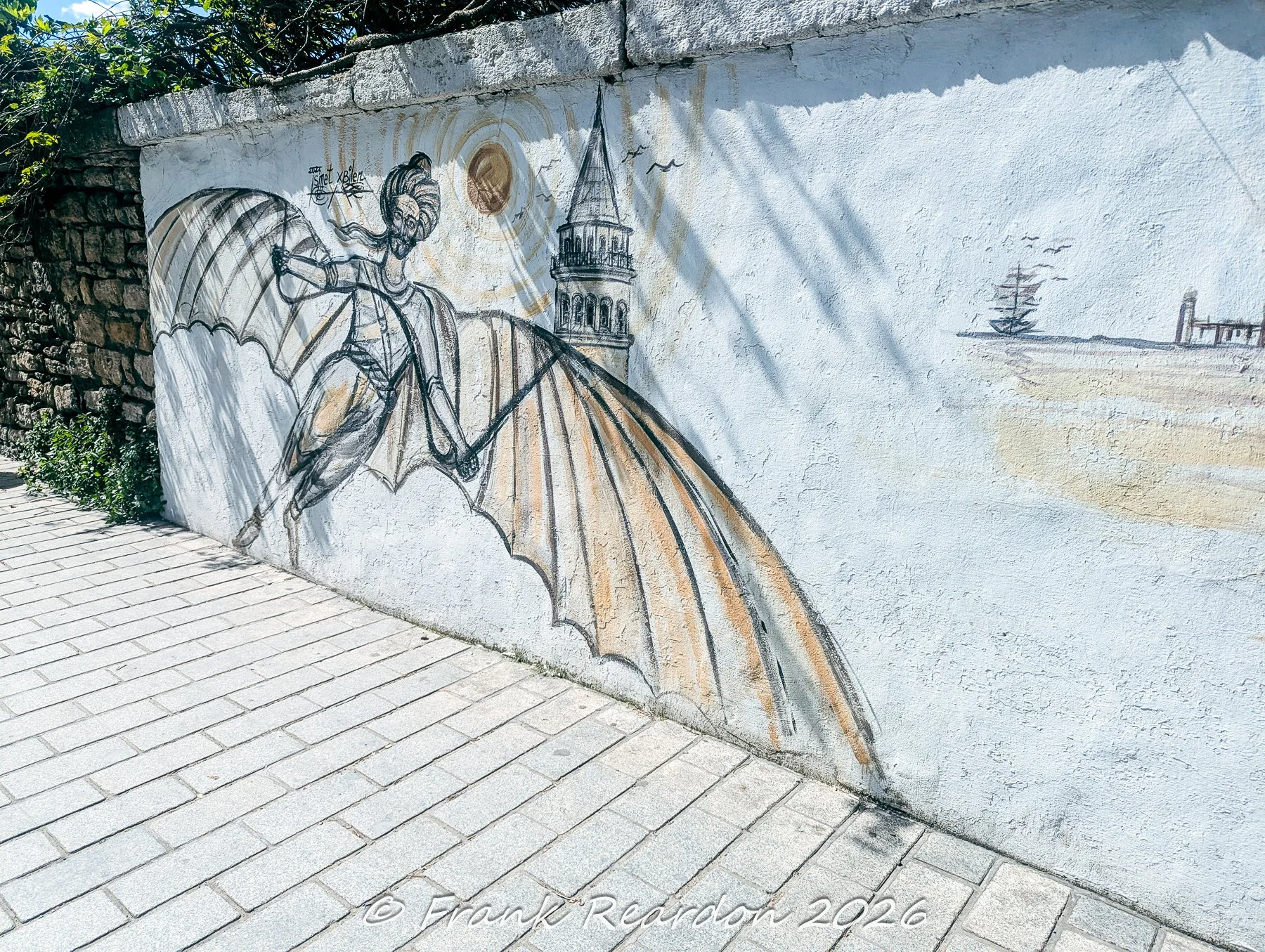 A painted wall mural depicting the legendary Ottoman aviator Hezarfen Ahmed Çelebi flying with artificial wings over the Galata Tower and Istanbul landscape.
