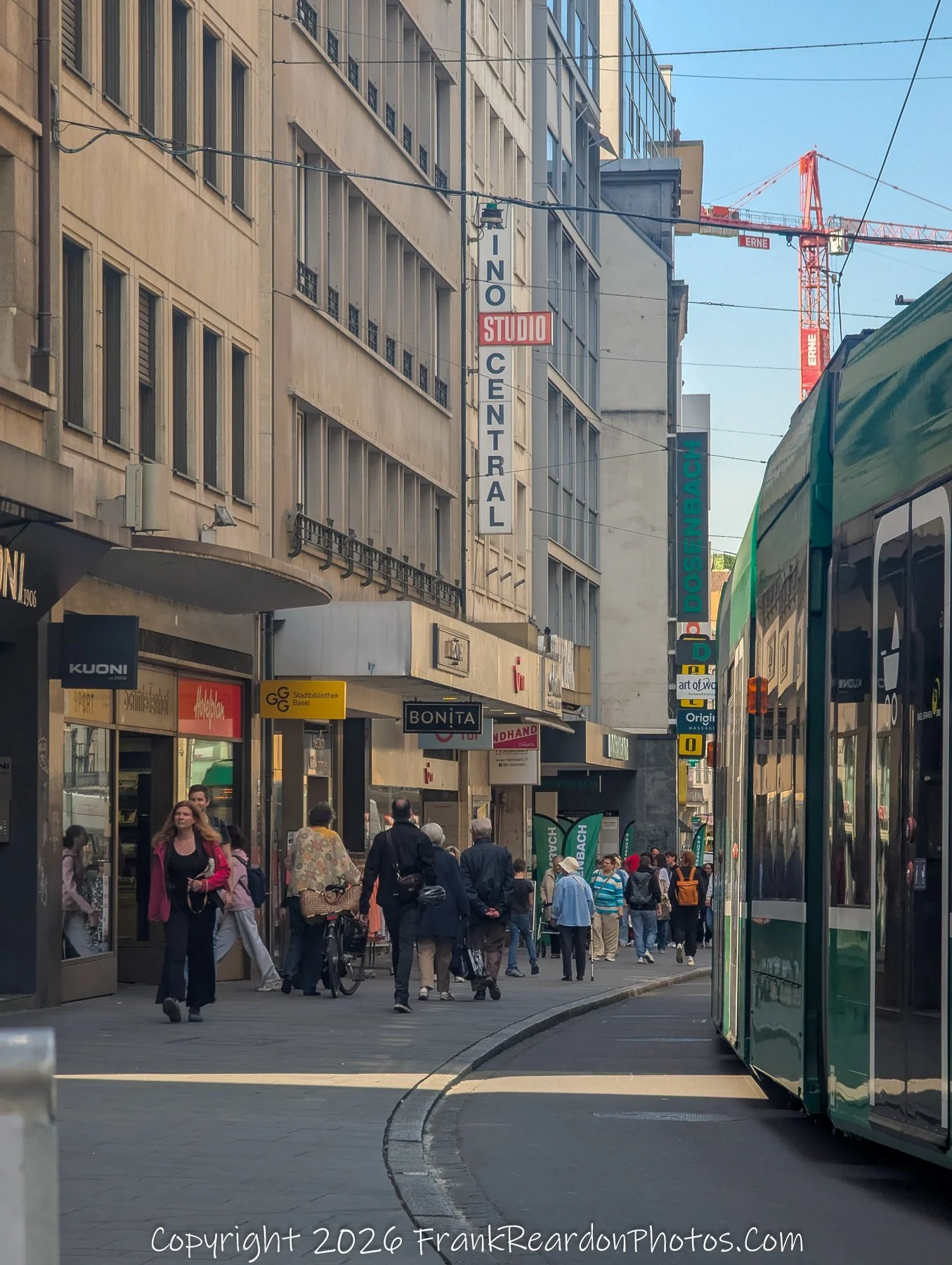 “Studio Street” Pedestrians and trams share a cinematic frame beneath the sign Kino Central.