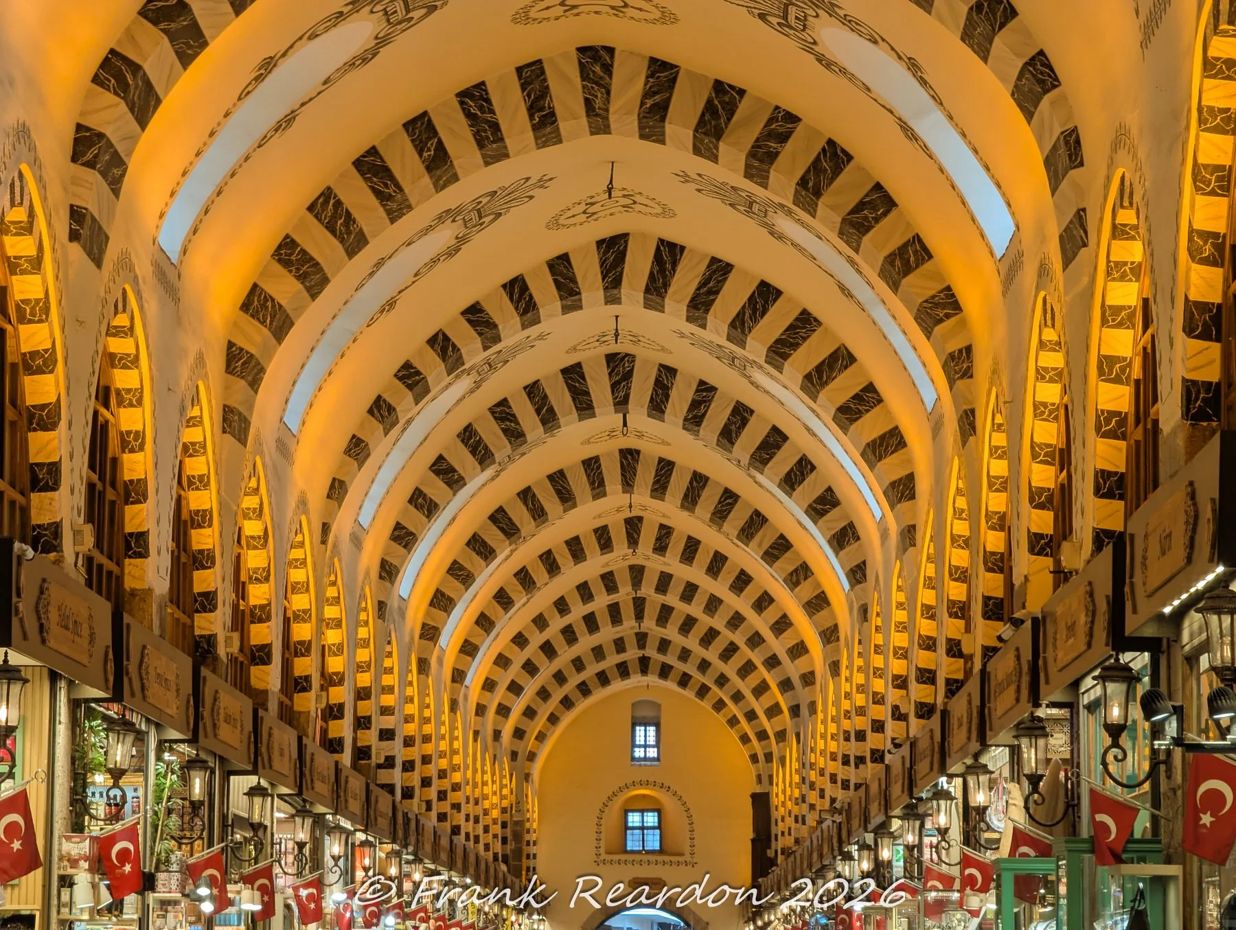Looking up at the decorated vaulted ceilings, striped stone arches, and architectural details within the Grand Bazaar (Kapaliçarsi).