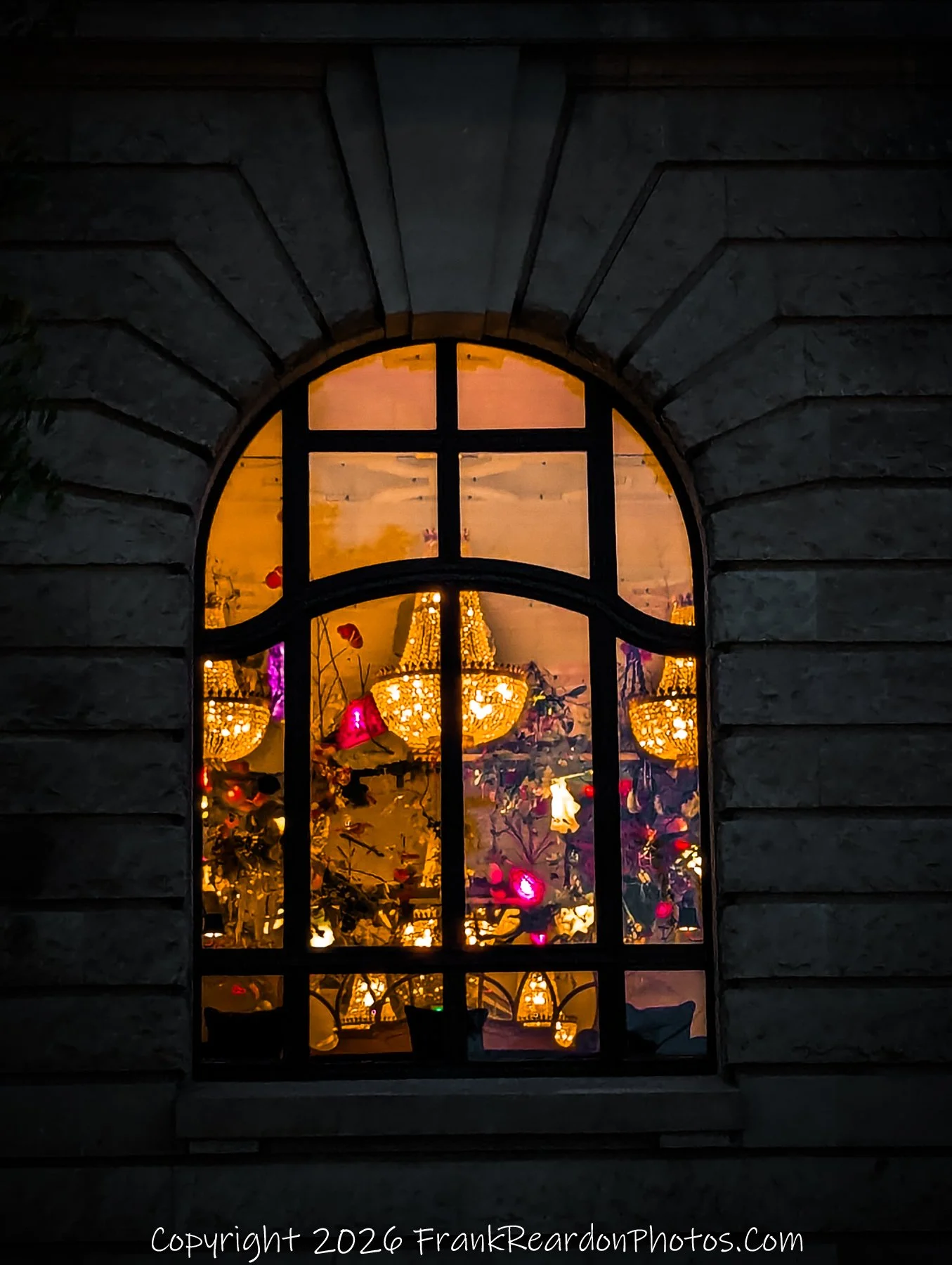 "Through the Glass" A close-up of a single arched window at night, highlighting the elegant interior decor and the play of light and shadow.