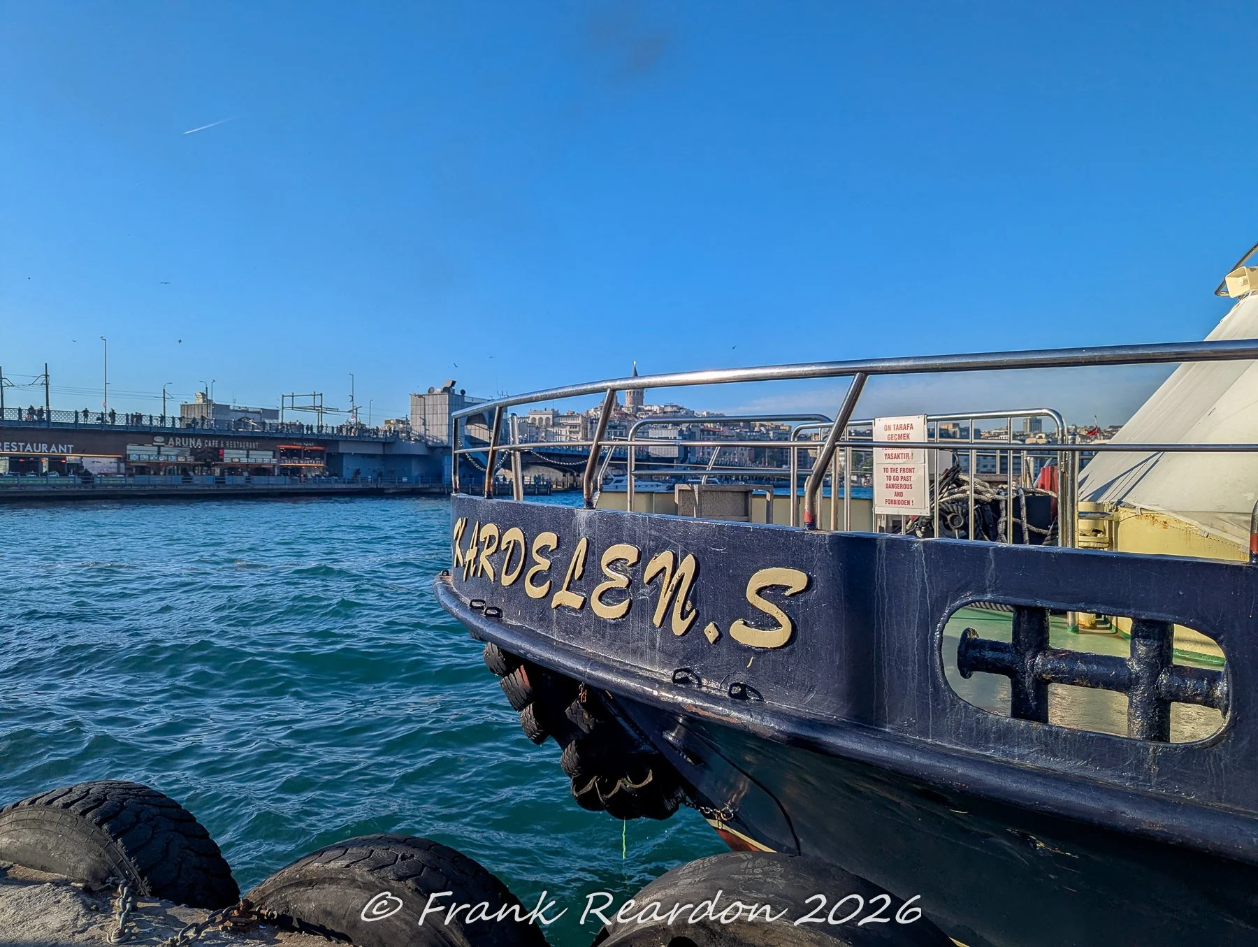 A detailed shot of the stern of a vessel named Kardelen-S moored along the water, with the urban skyline and the Galata Tower visible across the Golden Horn.