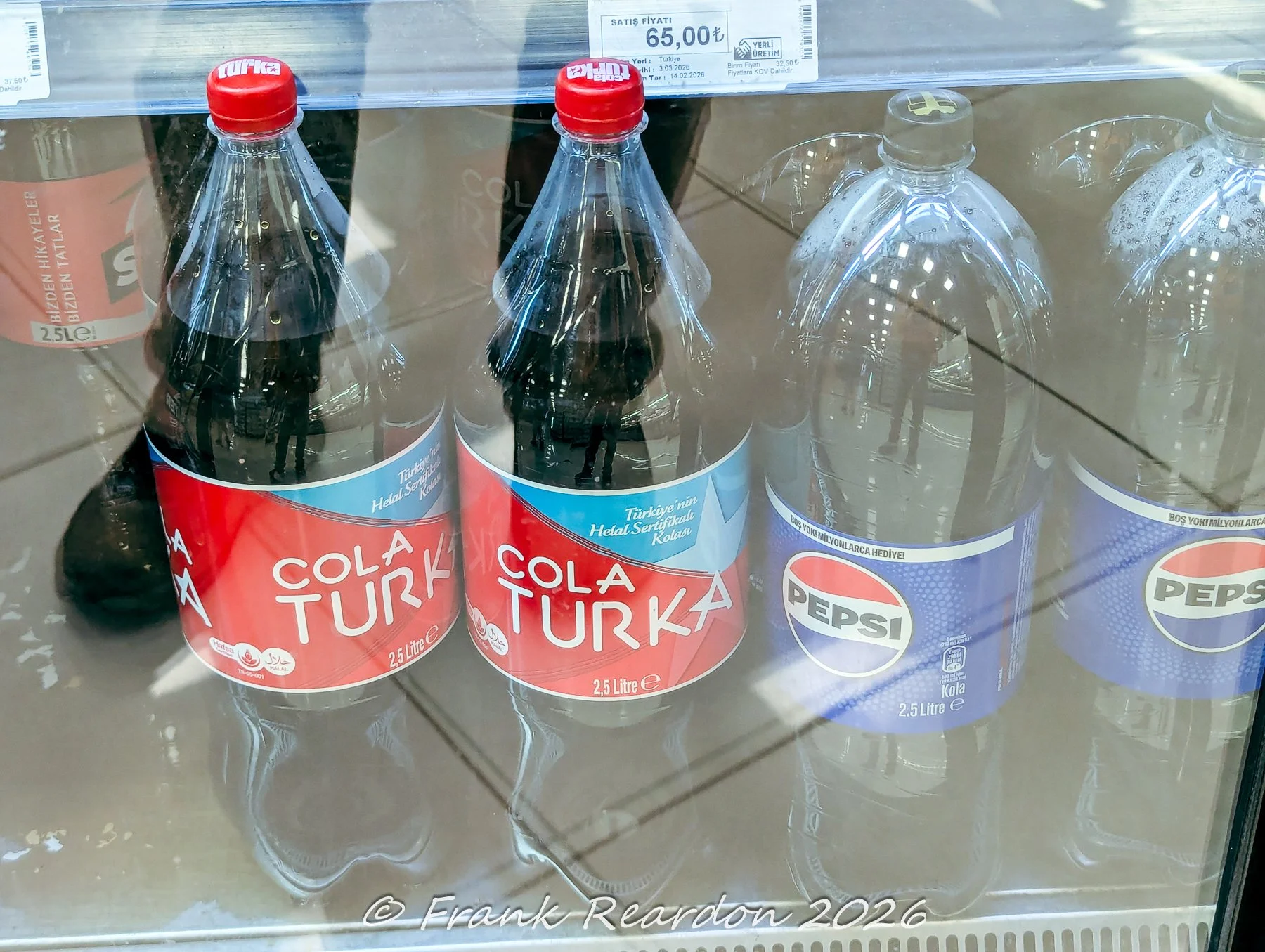 A grocery store refrigerator stocked with bottles of Cola Turka and Pepsi.