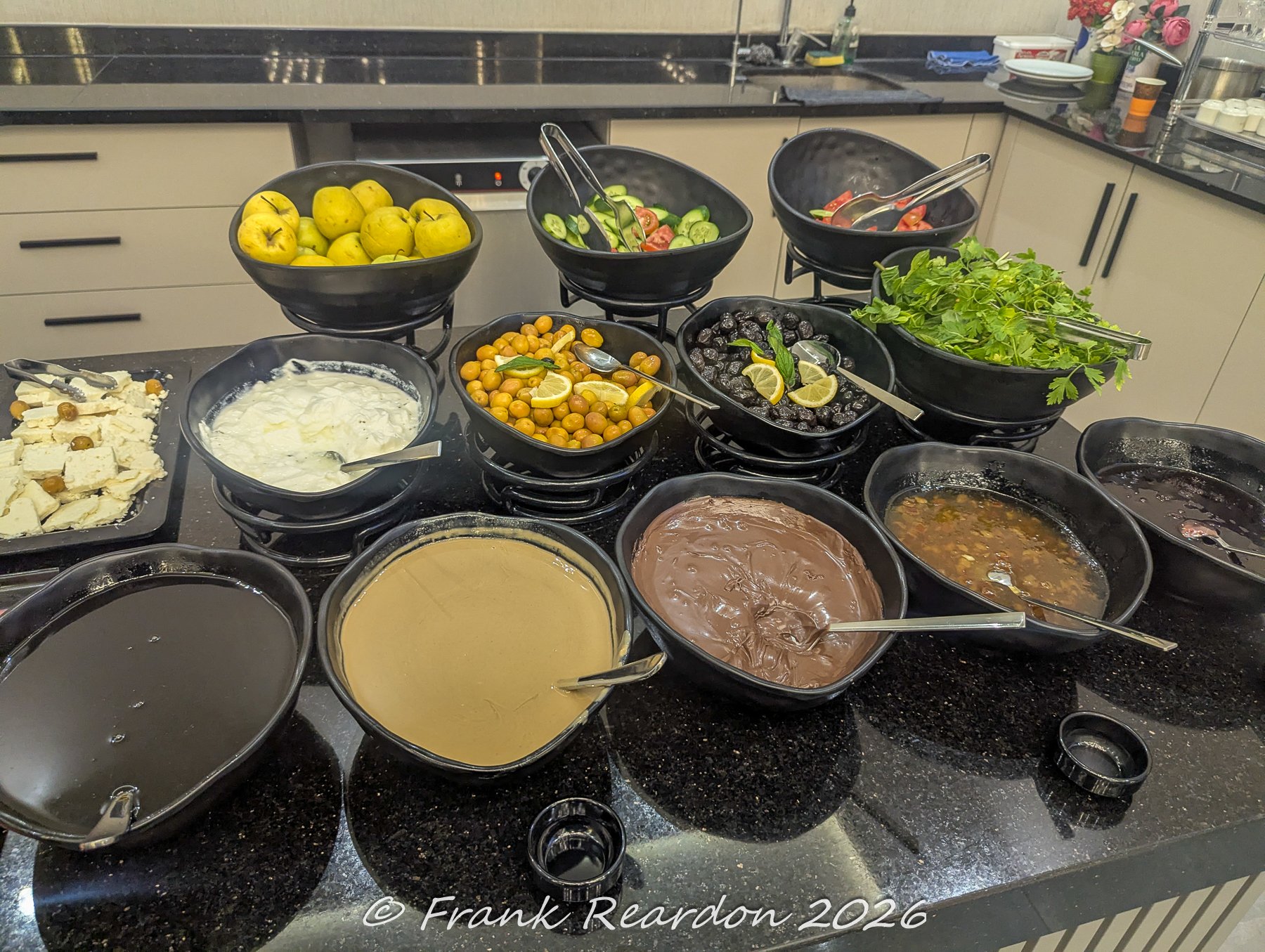 A rich spread of fresh local breakfast items, including olives, cheeses, spreads, and bowls of fruit at a dining establishment in Istanbul.