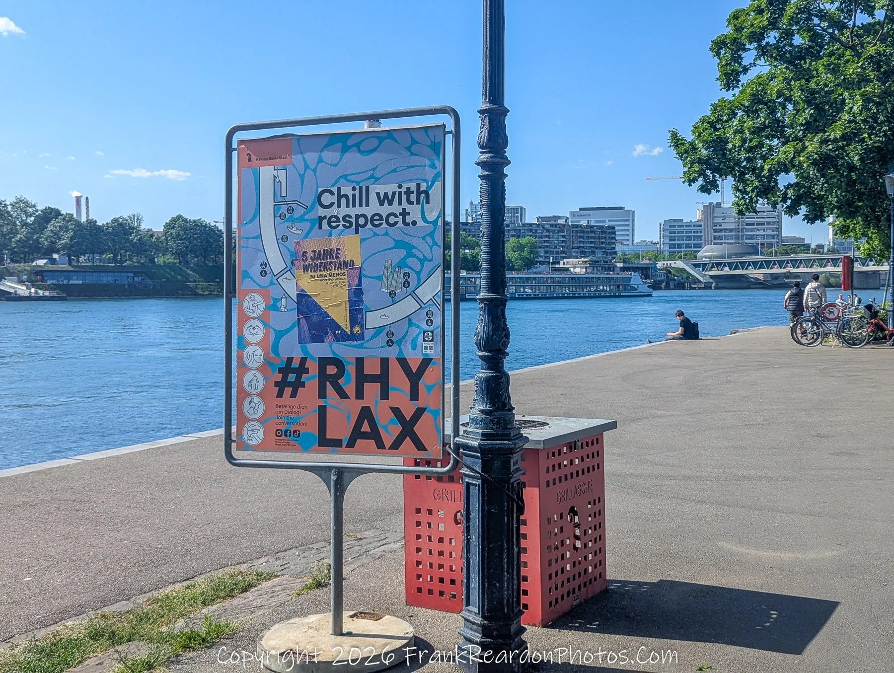 "Rhy Lax: A Call for Respectful Riverside Enjoyment" A public sign on the riverbank promoting the "#RHYLAX" campaign, which encourages people to "Chill with respect" while enjoying the area.