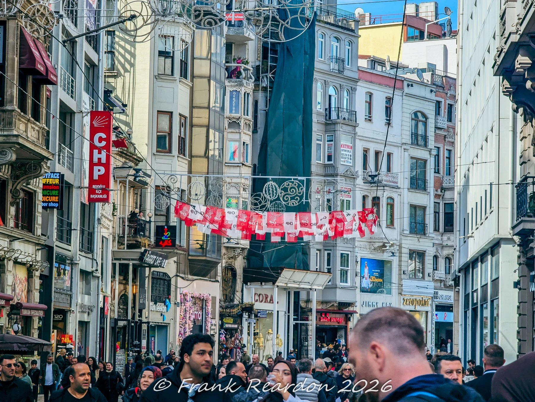 Historic multi-story buildings adorned with political and festive banners hanging across a narrow city street.