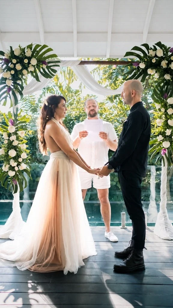 A couple exchanging vows beneath a floral arch