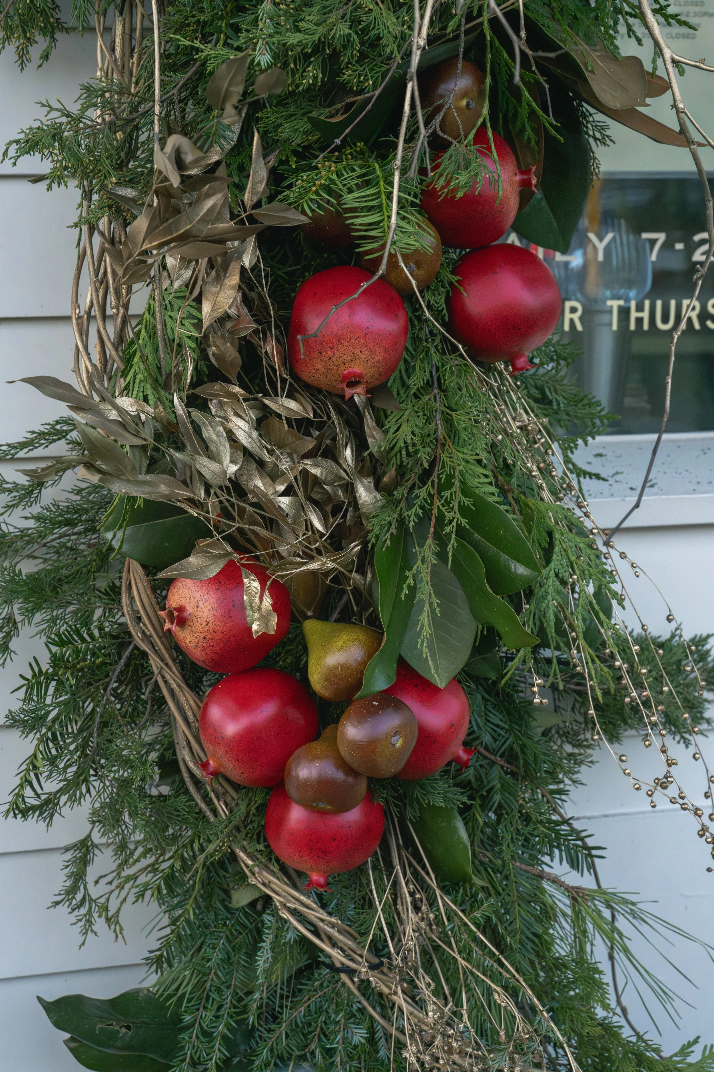 Pomegranates and pears nestled among evergreen foliage, magnolia leaves, and trailing branches in Perenn’s Christmas garland.