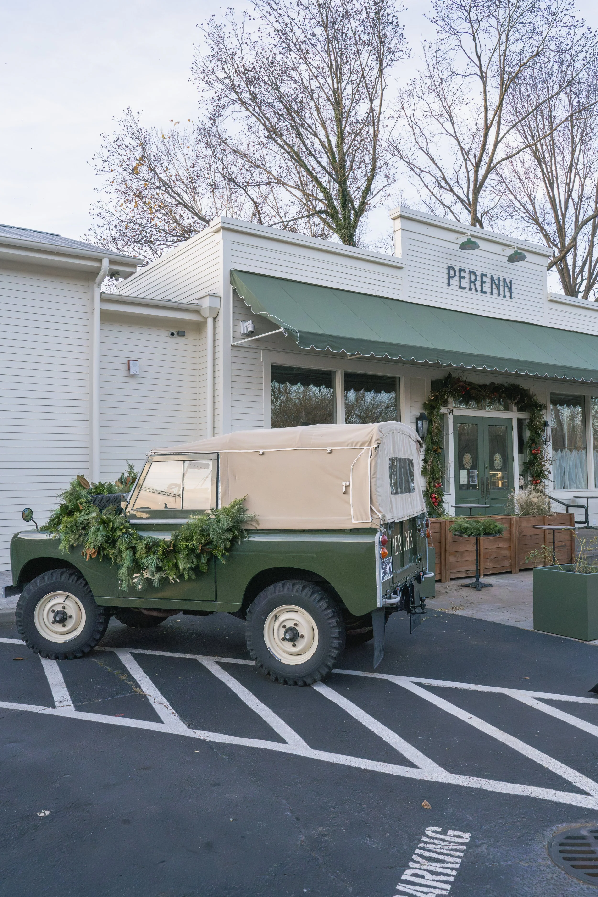 Perenn’s Franklin storefront with its green awning and a vintage Land Rover decorated for Christmas.