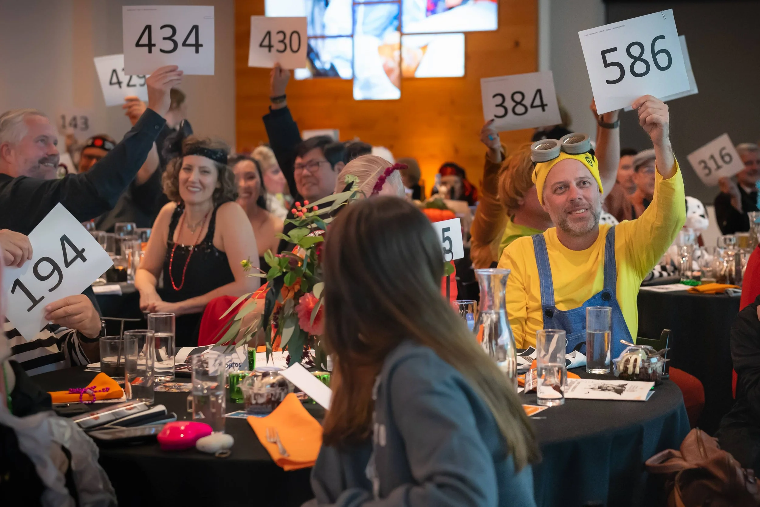 gala attendees holding up their bid cards at galaween 2024