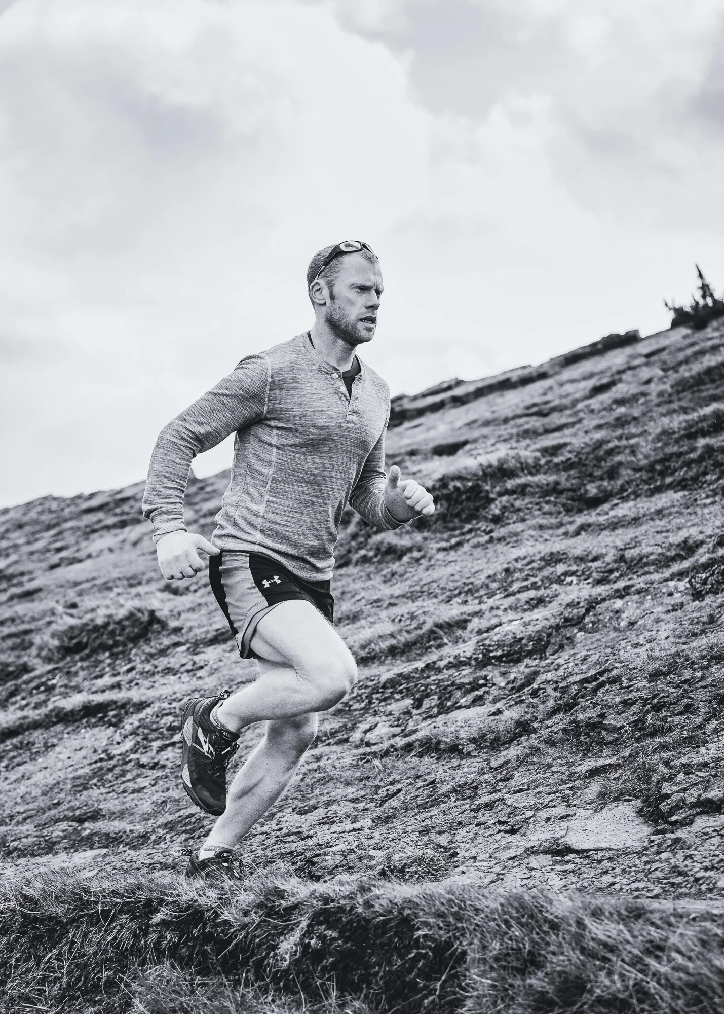 Personal Trainer, Gregor Ridley is running outdoors on a rugged hillside in Edinburgh, wearing athletic clothes and running shoes.