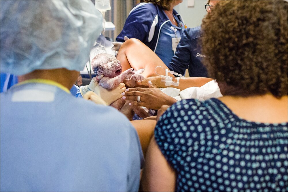 Newborn covered in vernix just born, mom reaches for her, Philadelphia Hospital Birth Photography