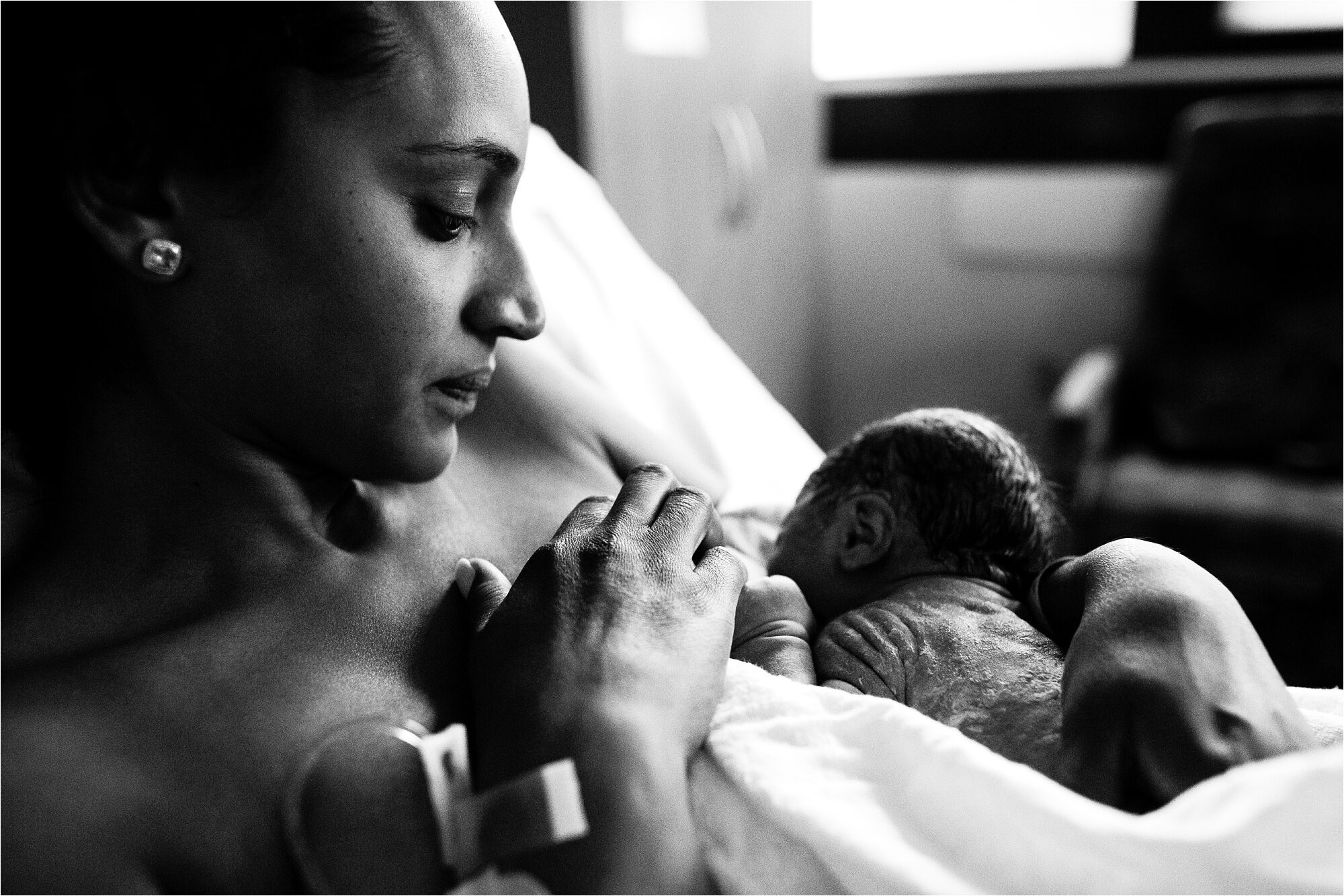 Newborn baby girl breastfeeds for the first time, mom admires her tiny fingers and wrinkled skin, Philadelphia Birth Photographer