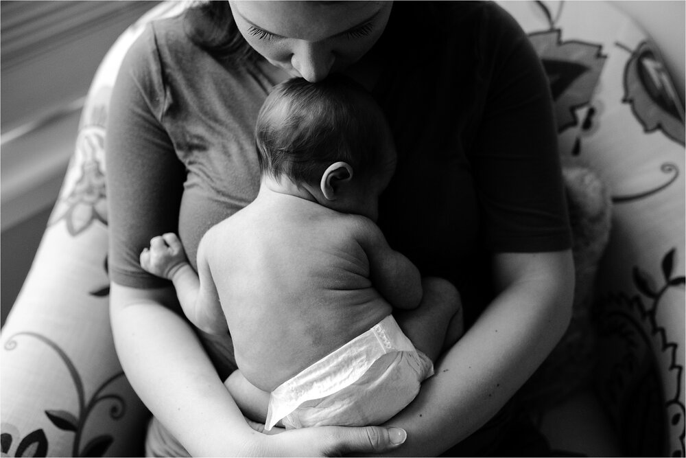 Overhead black and white portrait of new mom and her baby boy, kissing the top of his head, just in a diaper after breastfeeding, Philadelphia Newborn Photographer