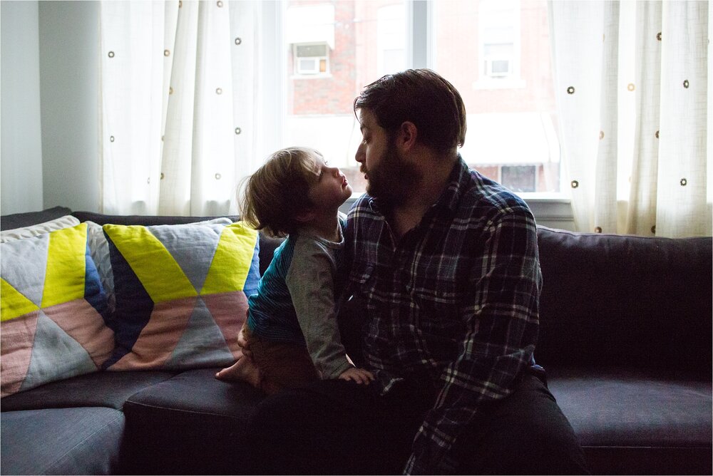 Father and son sit on the couch in front of the window, Philadelphia Fatherhood Photography
