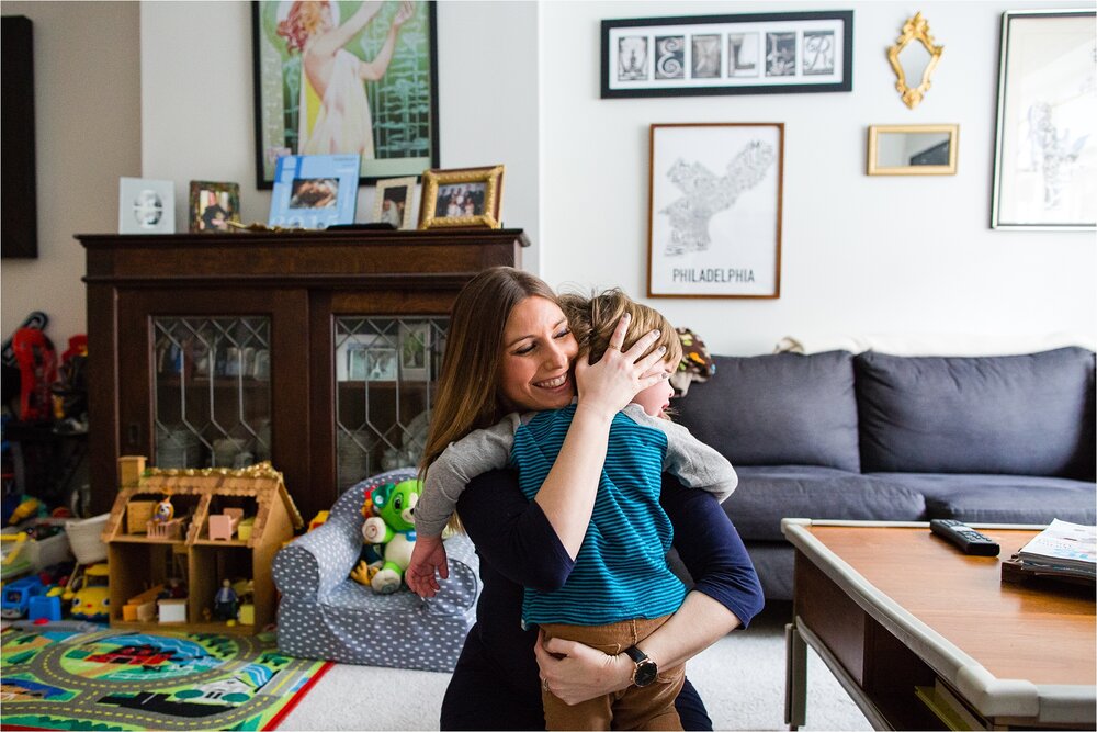 Mom embraces her toddler son in their living room full of toys and art on the walls, Philadelphia Family Photographer