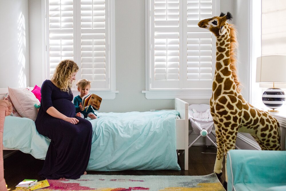 Pregnant mom reads with toddler daughter, giant giraffe toy, Philadelphia Family Photography