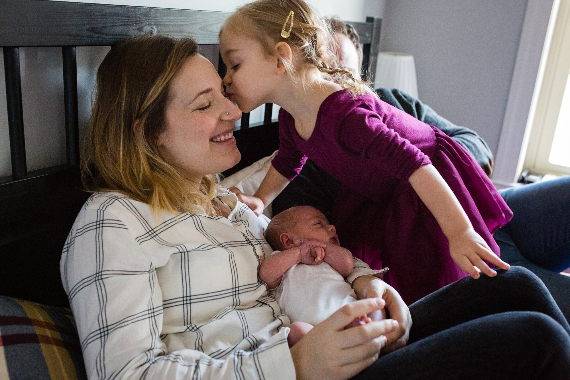 Big sister gives mom a kiss while she holds baby brother, Philadelphia family photographer