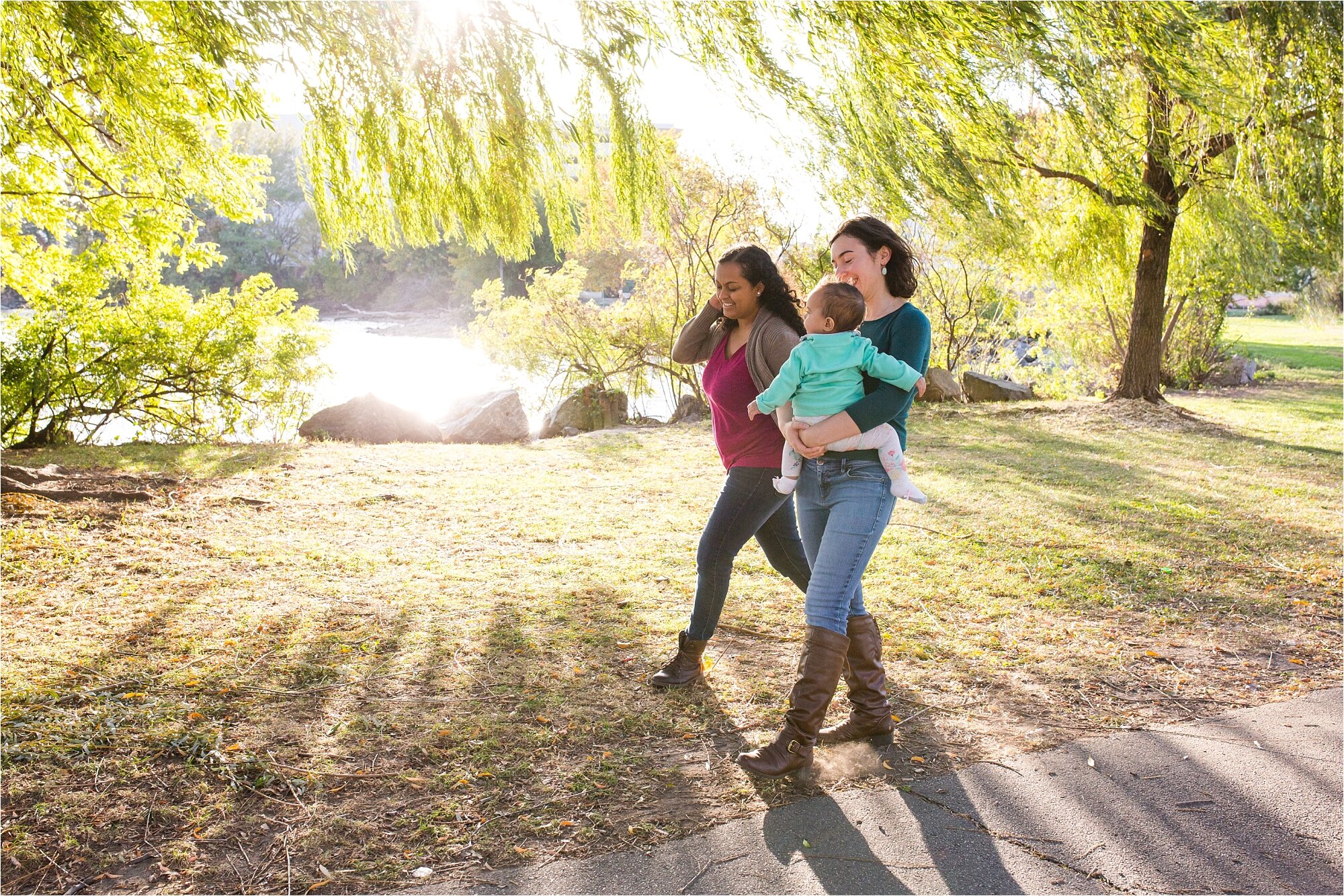 Lesbian gay mommies walk together in the sunset light with their baby daughter under the willow trees, Family Photography Philadelphia