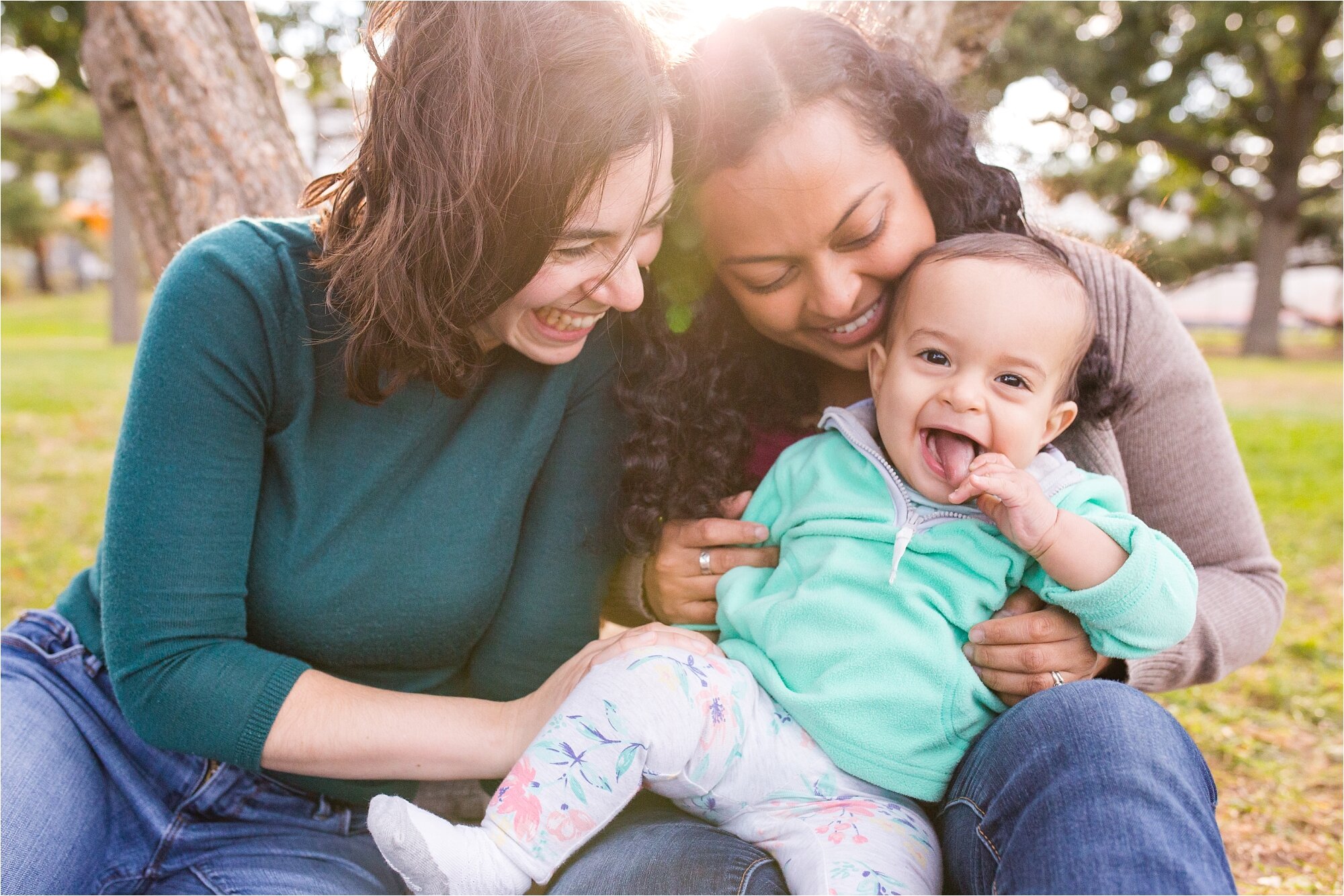 Lesbian gay mommies smiles while their baby daughter laughs and sticks out her tongue, Family Photographer Philadelphia