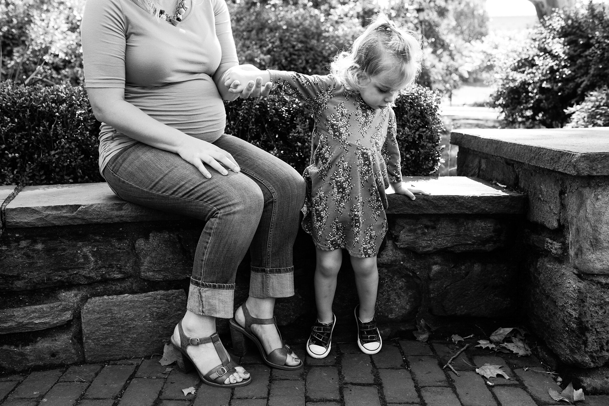Pregnant mom helps three year old daughter off the stone bench, black and white, Philadelphia Family Photograph