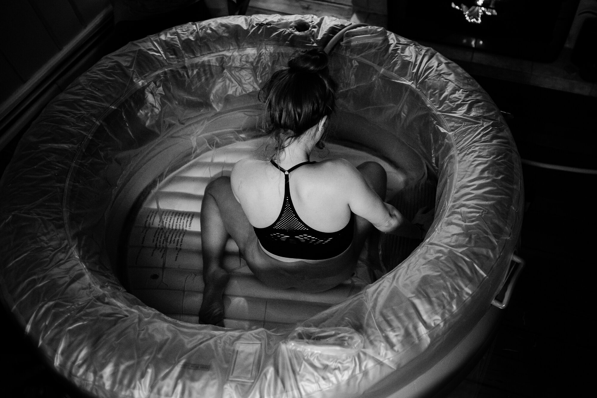 Black and white portrait from overhead of a women laboring in a birthing tub at home, birth photographer Philadelphia