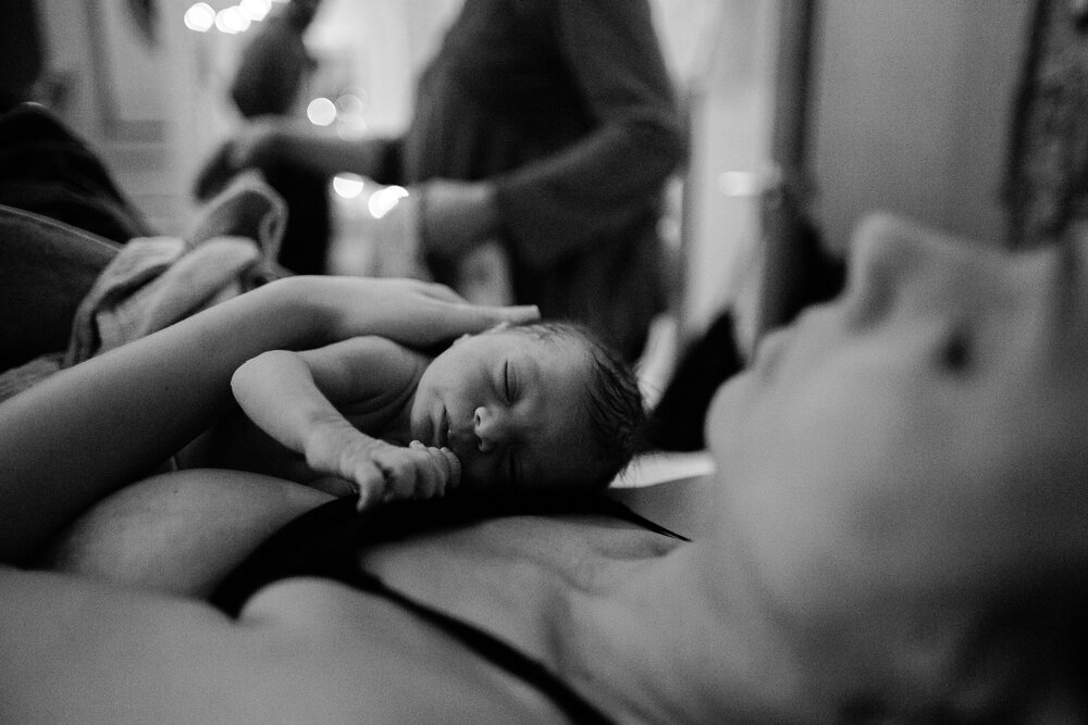 Minutes old baby girl rests on her mother's chest, skin to skin, Philadelphia home birth photographer
