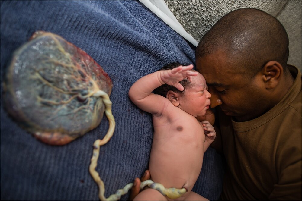 Black father bonds with his new born baby son, still attached by umbilical cord to placenta, lotus birth Photographer Philadelphia
