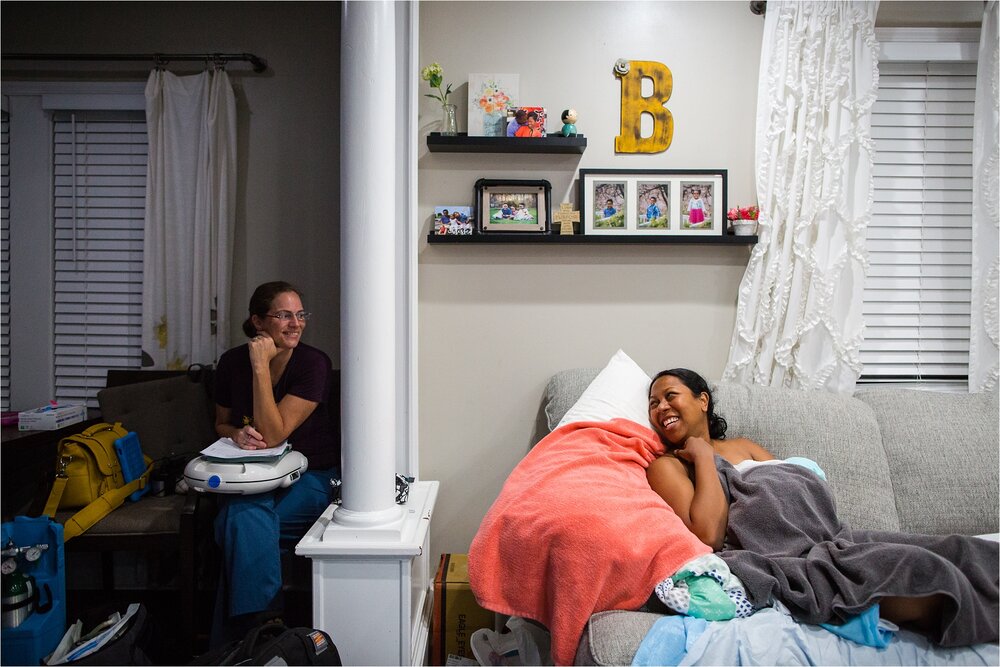 Black mother smiles and chats with her midwife after home birth, home birth Photographer Philadelphia