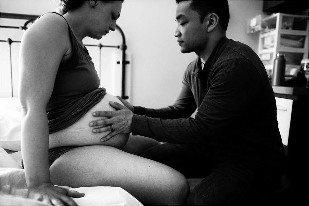 Mom works through a contraction while husband lovingly holds her belly, Philadelphia birth center photography