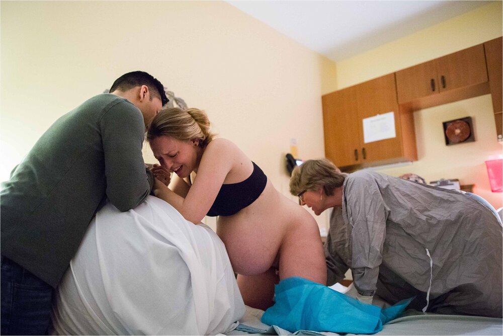 Pregnant mom vocalizes during a contraction with husband's support, midwife and nurse prepare for delivery, Philadelphia birth center photography