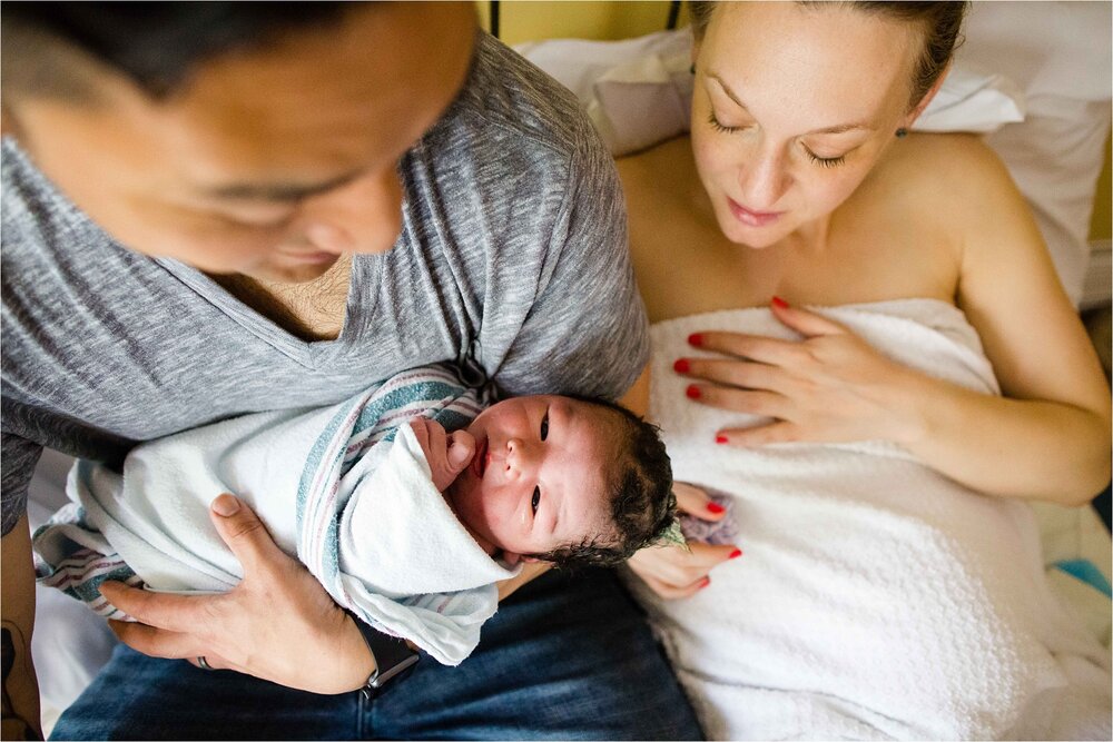 Mom and dad gaze lovingly at new baby boy after just being born,Philadelphia birth center photographer