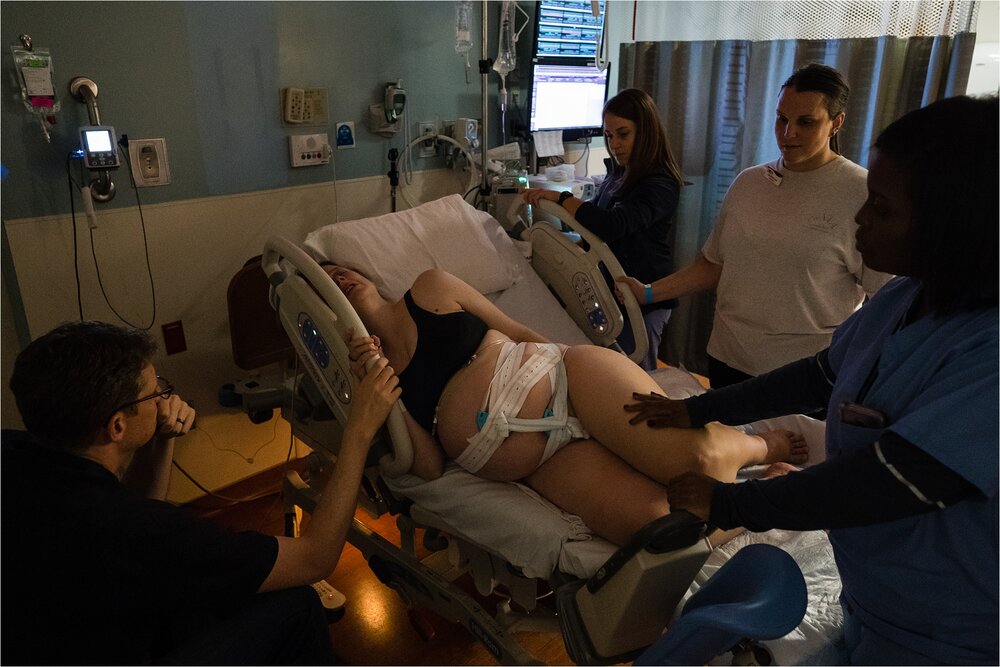 Mother in labor comforted by husband, midwife, doula, nurse, at hospital, Philadelphia Birth Photographer