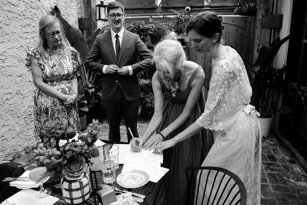 Mother of the bride signs marriage license as mother of the groom watches with happy couple, Philadelphia documentary wedding photography