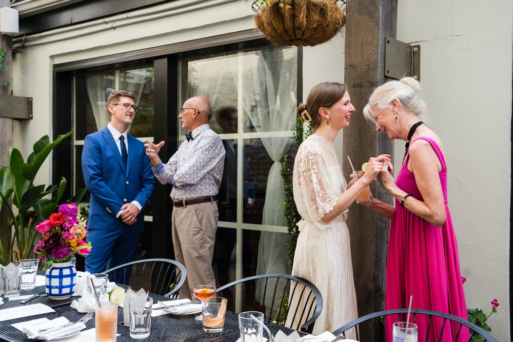 Candid shot of bride and mom laughing together, groom and dad chatting, Philadelphia wedding photographer